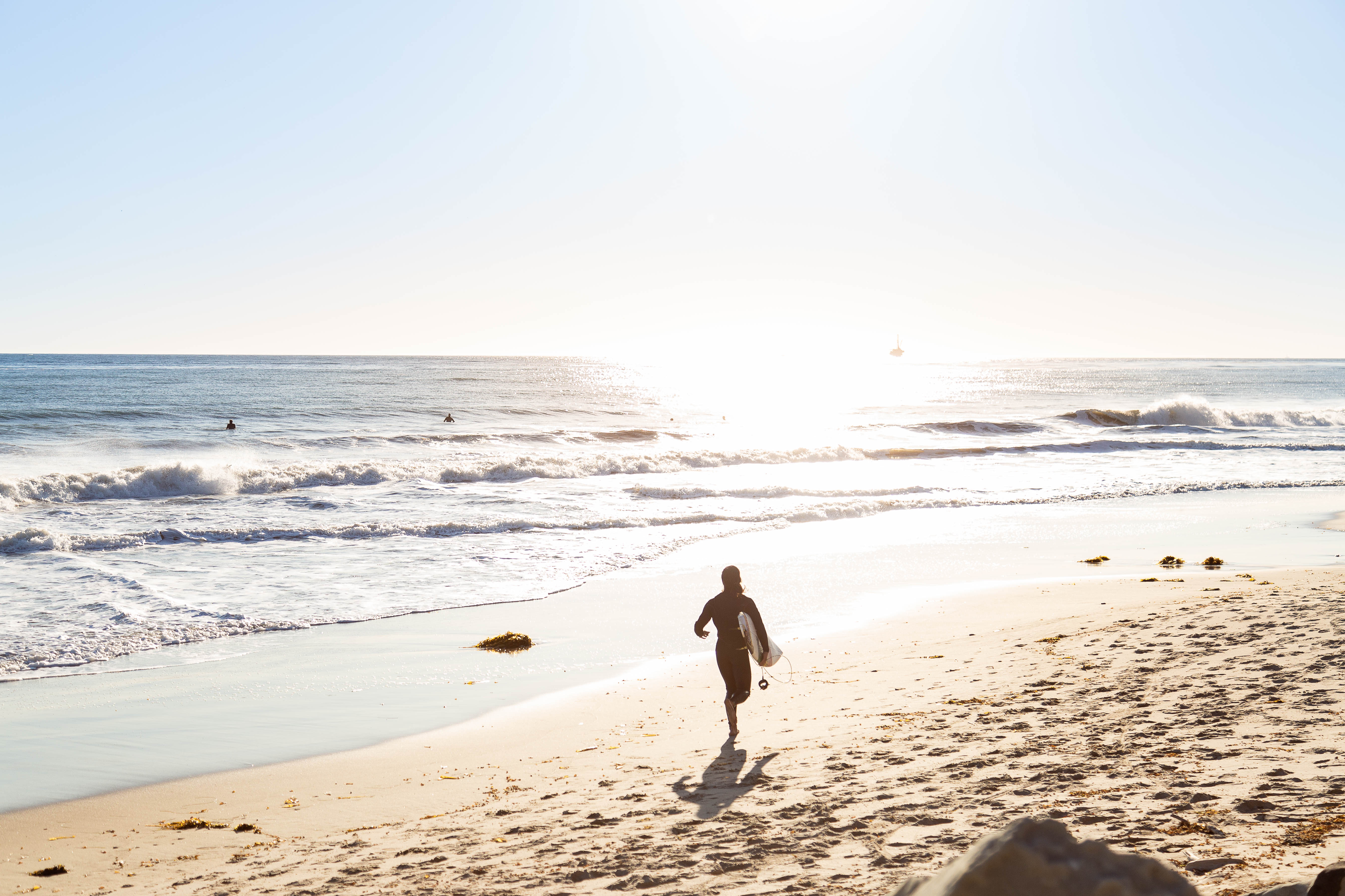 This is an image of three student surfers on the beach.