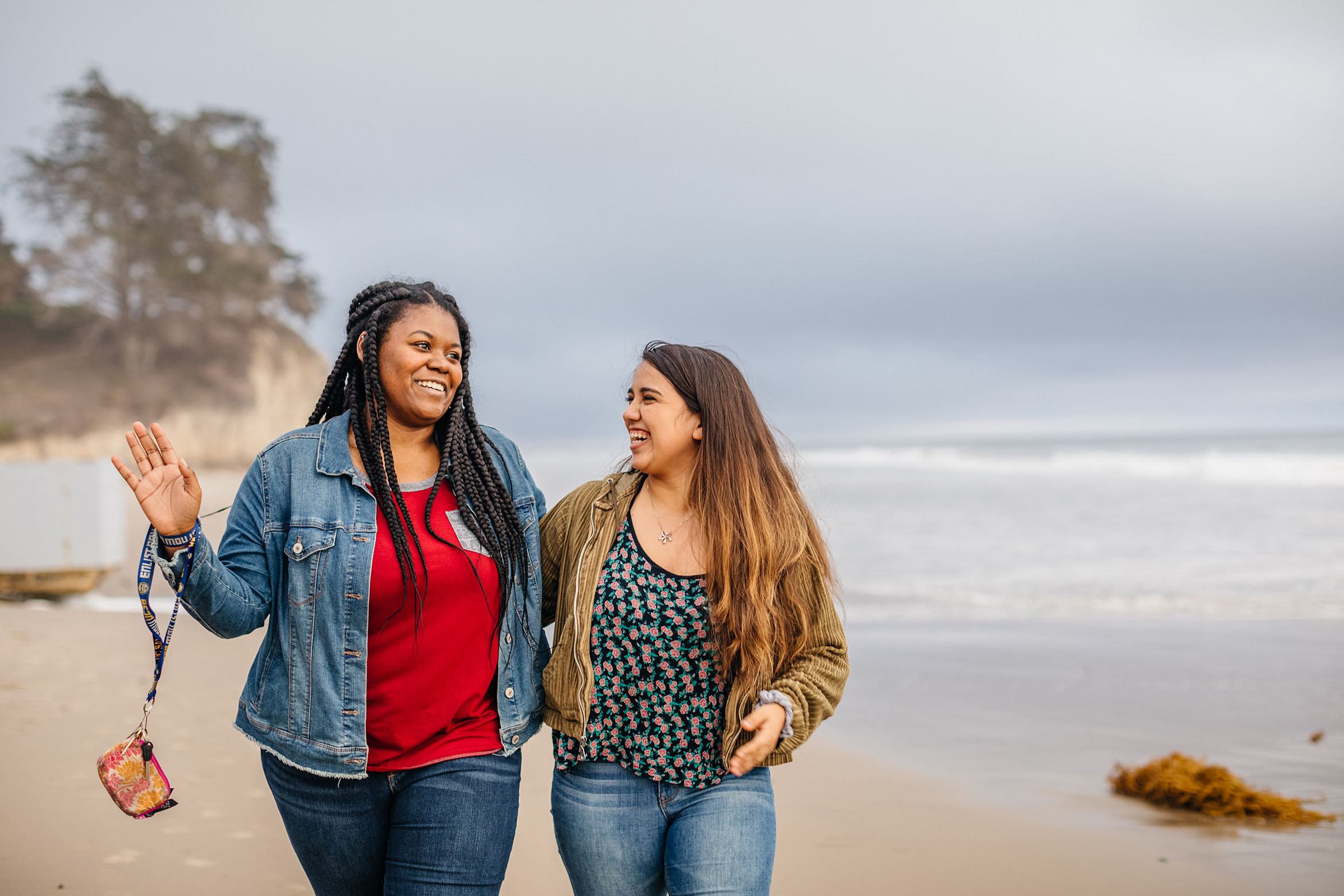 This is an image of two students chatting and walking on the beach.